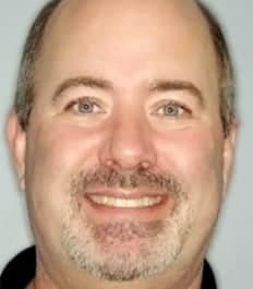 A smiling man with a friendly expression, close-up portrait