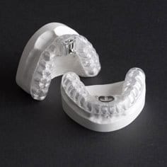 Clear dental night guard on black background, orthodontic appliance for teeth protection.